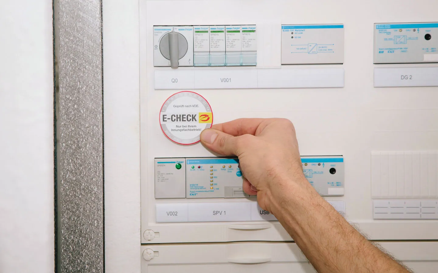 E-CHECK - Mitarbeiter klebt in der Verteilung die E-CHECK Plakette an · Winter Elektro